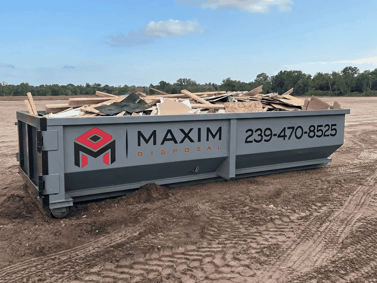 Roll-off dumpster loaded level with construction and demolition debris on an open lot in Southwest Florida