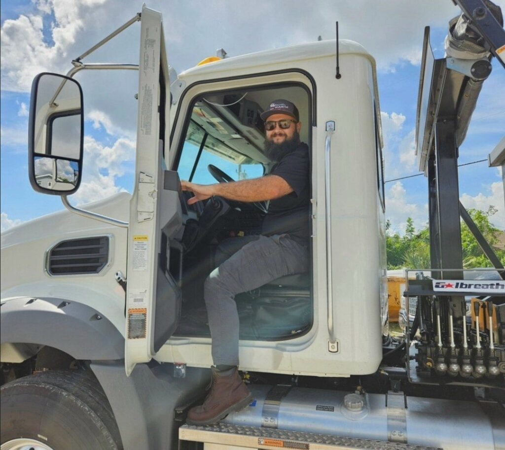 Maxim Disposal driver in the cab of a roll-off truck in Southwest Florida