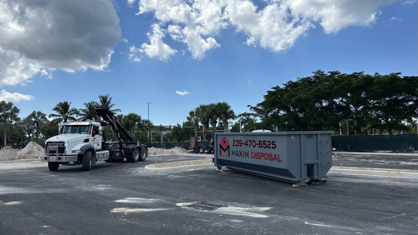 Maxim Disposal truck delivering a roll-off container to a commercial construction site in Southwest Florida