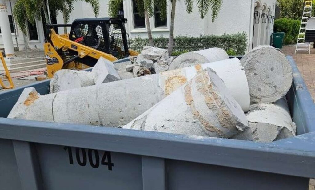 Concrete-only roll-off container loaded with broken concrete columns and footings at a house under construction