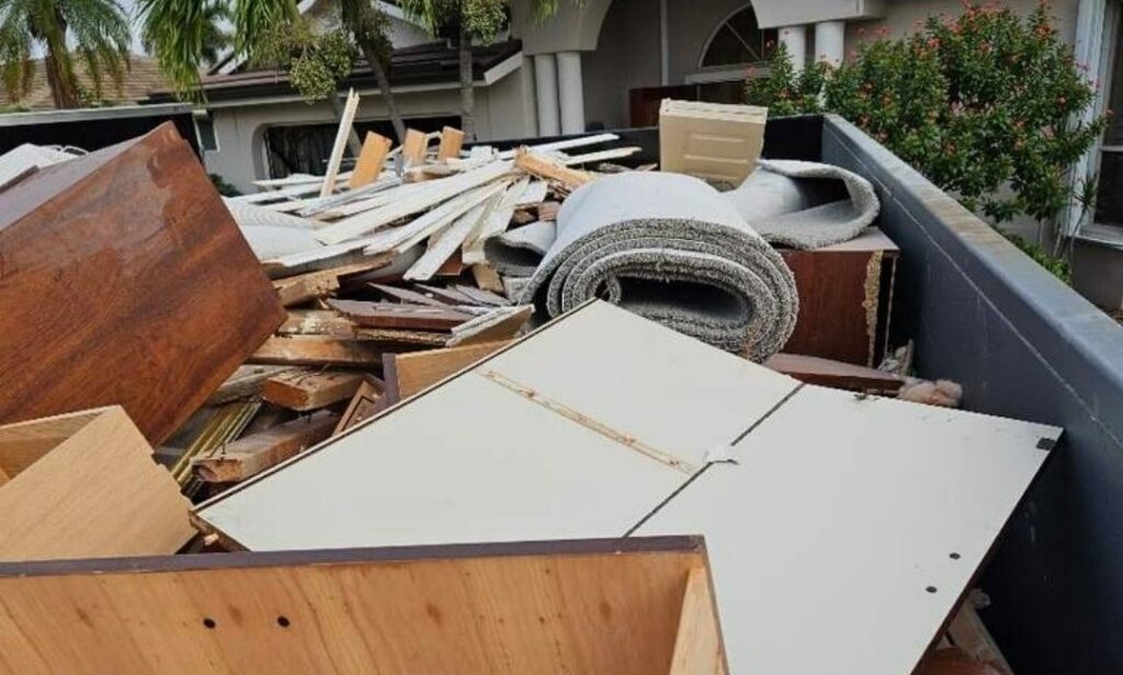 Roll-off container loaded with cabinets, carpet and trim from a home remodel