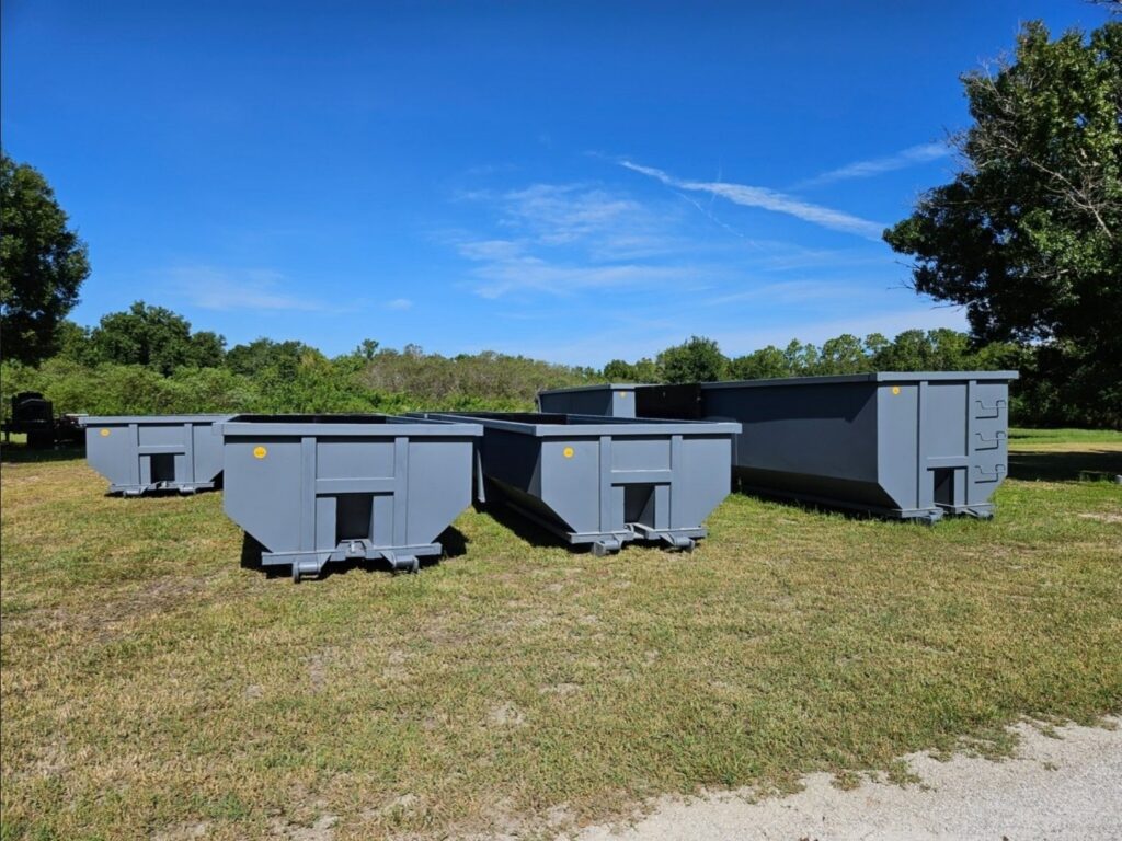Four Maxim Disposal roll-off containers of different sizes staged in the yard