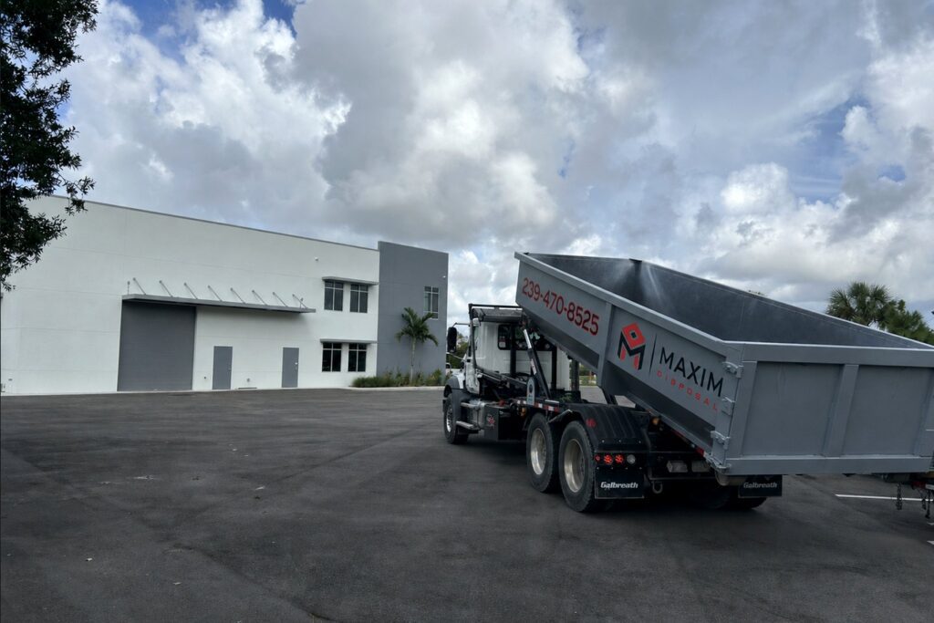 Maxim Disposal roll-off truck setting a 30 yard container at a commercial building in Fort Myers, Florida