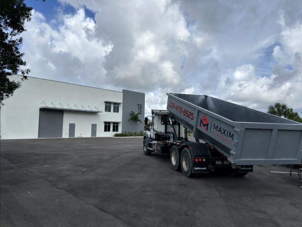 Maxim Disposal roll-off truck setting a 30 yard container at a commercial building in Fort Myers, Florida